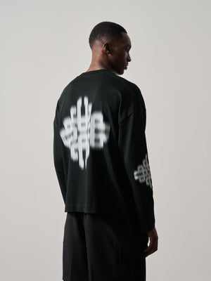 Person wearing a black outfit with white branded artwork on a plain background