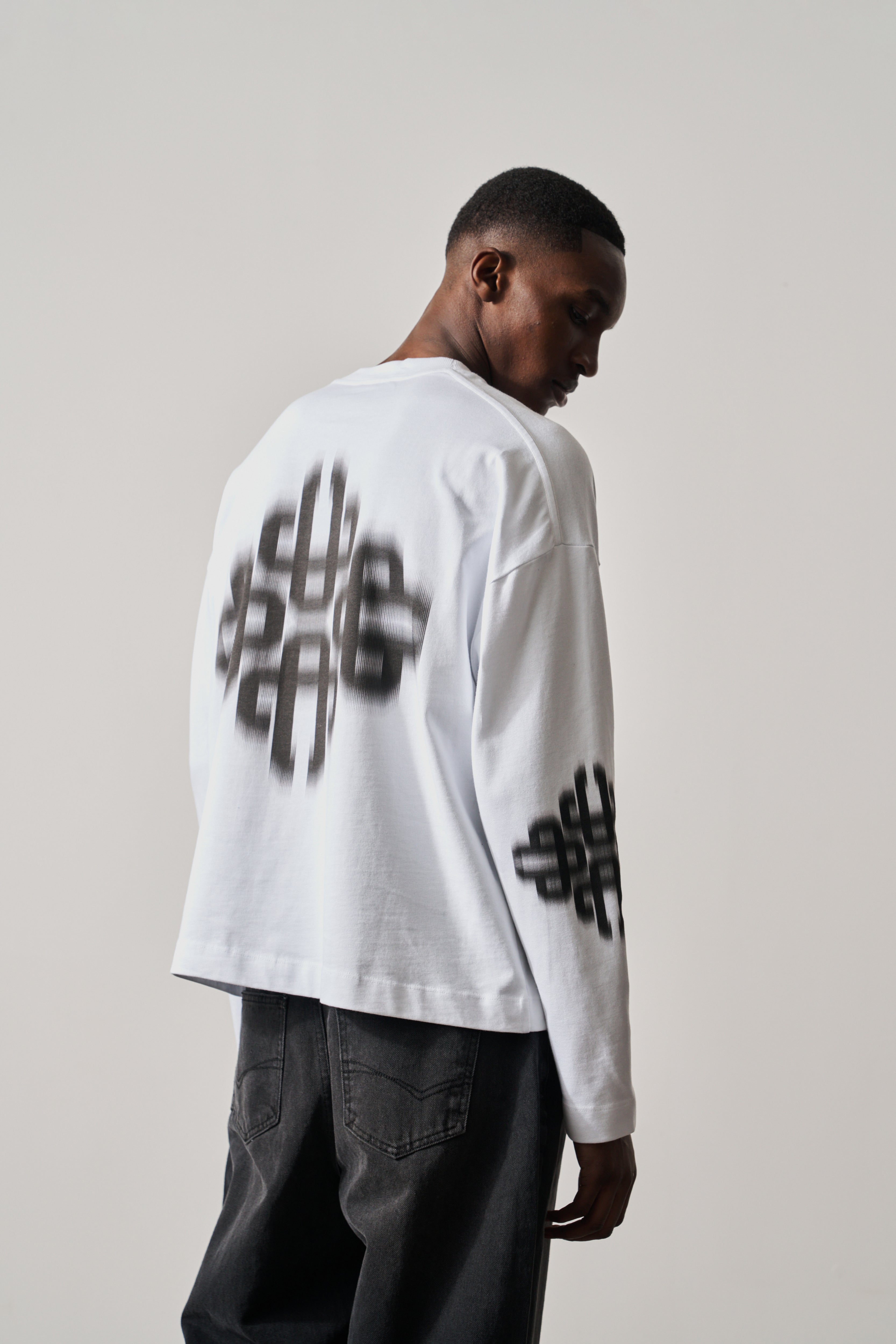 Person wearing a white long-sleeve t-shirt with black text design on a plain background