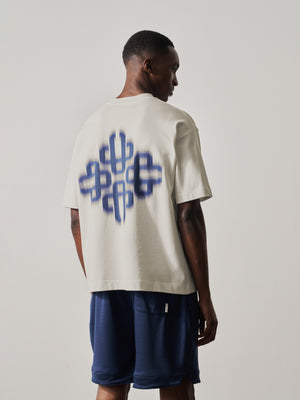 Person wearing a white t-shirt with a blue graphic design on the back, standing against a plain background.